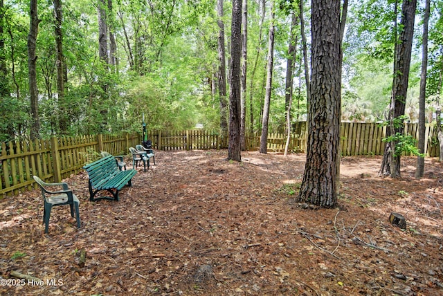 view of yard featuring a fenced backyard and a view of trees