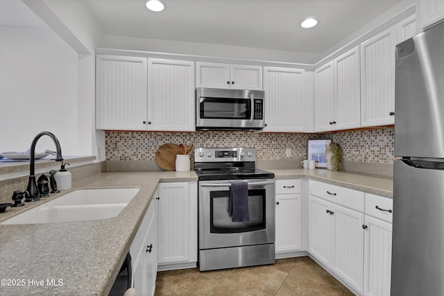 kitchen featuring tasteful backsplash, white cabinets, stainless steel appliances, and a sink