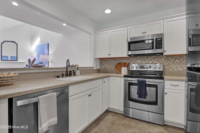 kitchen with a sink, tasteful backsplash, white cabinetry, stainless steel appliances, and light countertops