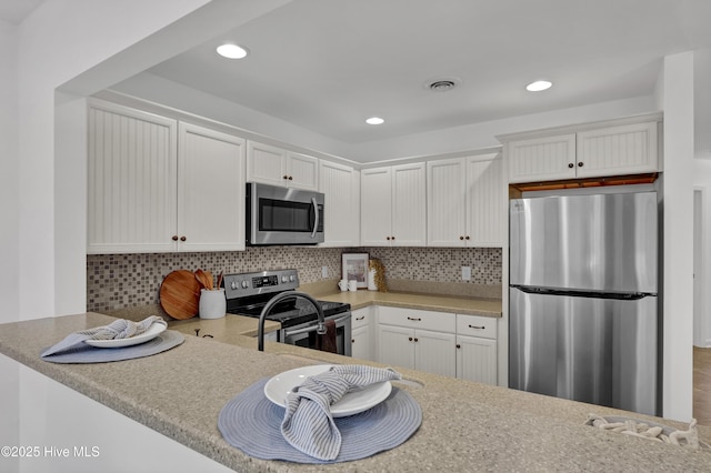 kitchen with white cabinets, tasteful backsplash, visible vents, and stainless steel appliances