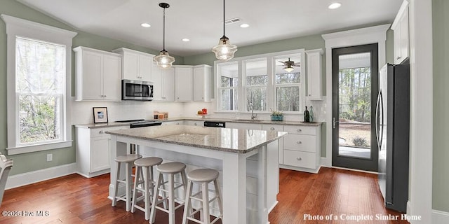 2760 Alvernia Dr, Castle Hayne, NC 28429 - kitchen with stainless steel appliances, white cabinetry, a center island, dark wood-style flooring, and a breakfast bar area