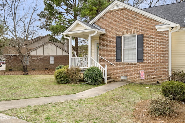 view of front of house with crawl space, a front yard, brick siding, and roof with shingles