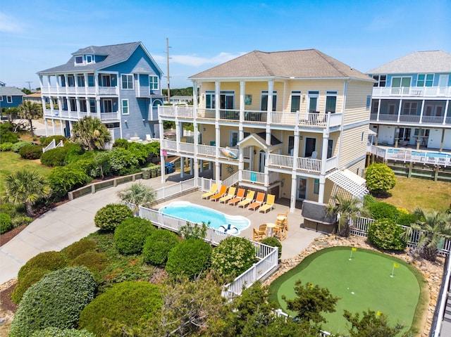 rear view of house featuring a patio area, a balcony, a fenced backyard, and a community pool