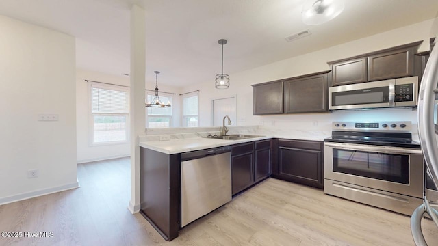 kitchen featuring light wood finished floors, visible vents, dark brown cabinets, appliances with stainless steel finishes, and a sink