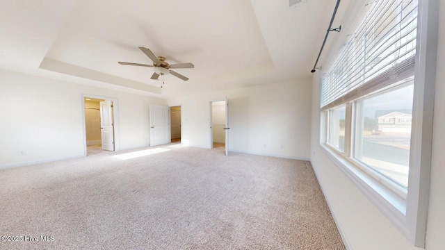 unfurnished bedroom featuring a tray ceiling, light carpet, baseboards, and visible vents