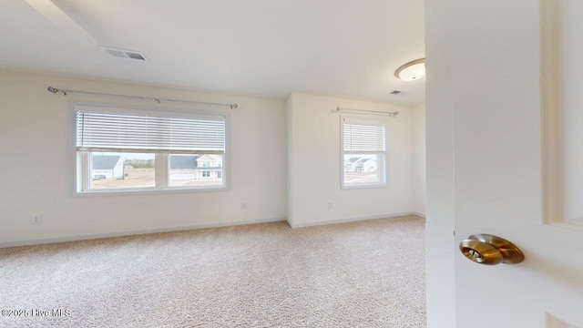 carpeted spare room with visible vents and baseboards