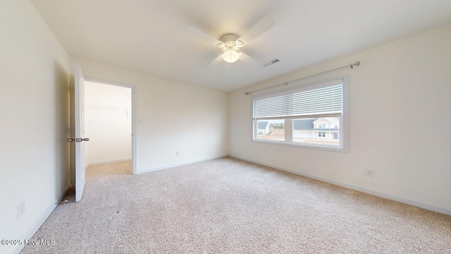 spare room featuring ceiling fan, baseboards, visible vents, and light carpet