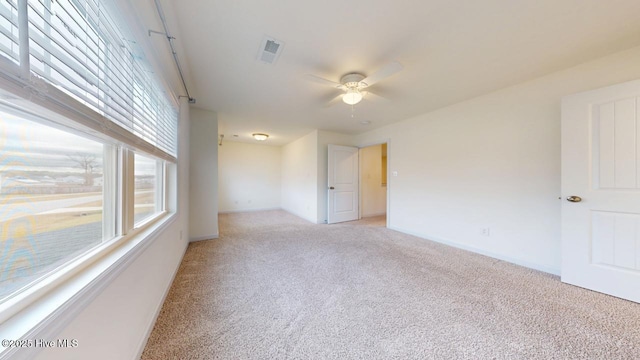 empty room with light carpet, visible vents, baseboards, and a ceiling fan