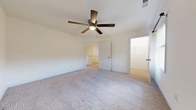 unfurnished bedroom featuring a ceiling fan, baseboards, visible vents, a spacious closet, and light carpet