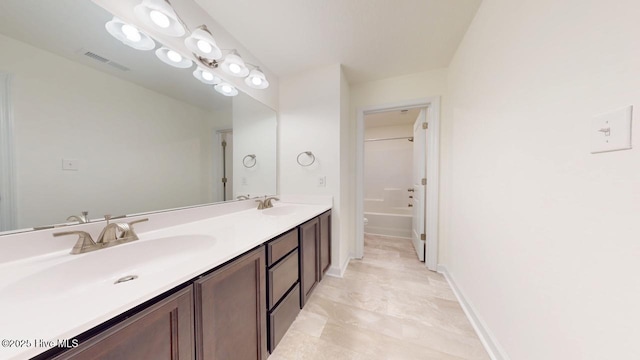 bathroom featuring visible vents, baseboards, toilet, double vanity, and a sink