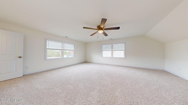 empty room featuring baseboards, light colored carpet, a ceiling fan, and vaulted ceiling