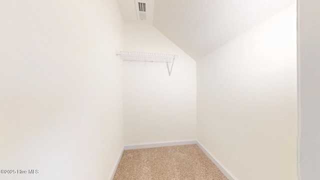 walk in closet featuring lofted ceiling, light colored carpet, and visible vents