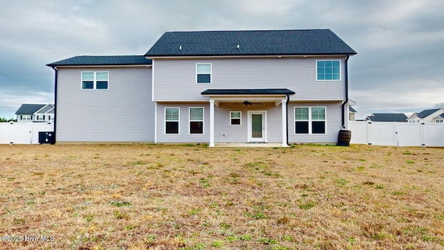 back of house with a yard, a fenced backyard, ceiling fan, and a gate