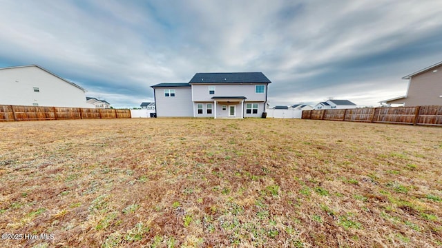 back of house with a lawn and a fenced backyard