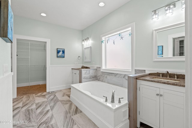 449 E Fourth St, Ocean Isle Beach, NC 28469 - bathroom featuring a wainscoted wall, two vanities, a garden tub, recessed lighting, and a walk in closet