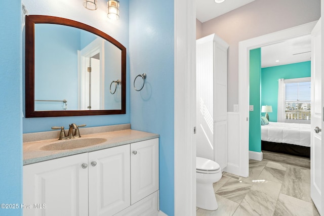 449 E Fourth St, Ocean Isle Beach, NC 28469 - ensuite bathroom featuring vanity, marble look tile flooring, toilet, and baseboards