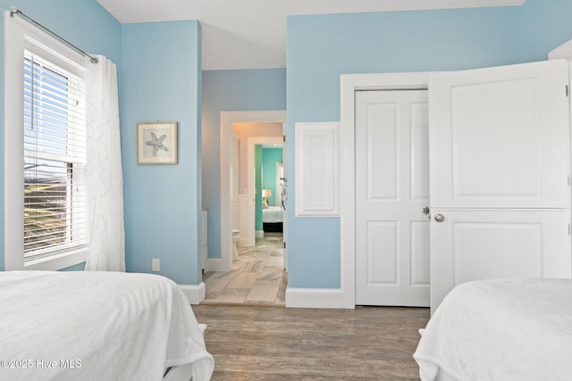 449 E Fourth St, Ocean Isle Beach, NC 28469 - bedroom with multiple windows, baseboards, a closet, and wood finished floors