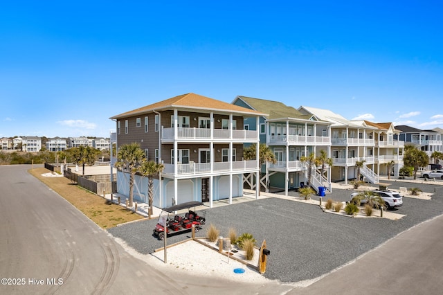 449 E Fourth St, Ocean Isle Beach, NC 28469 - view of building exterior with a residential view, a garage, and gravel driveway