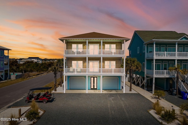 449 E Fourth St, Ocean Isle Beach, NC 28469 - back of property featuring a balcony, a garage, gravel driveway, and french doors