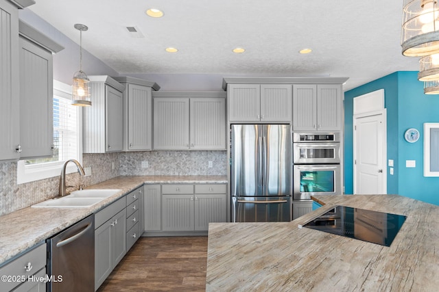449 E Fourth St, Ocean Isle Beach, NC 28469 - kitchen with appliances with stainless steel finishes, a sink, decorative backsplash, dark wood-type flooring, and gray cabinetry