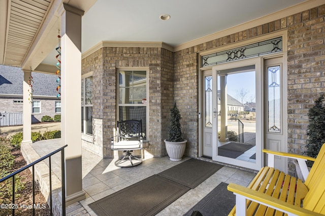 property entrance with a porch and brick siding