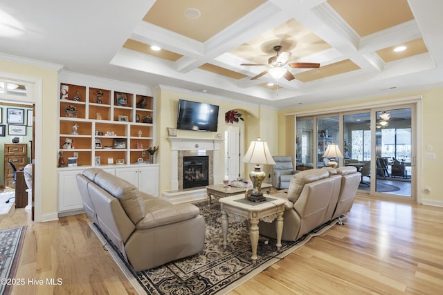 living area featuring ornamental molding, coffered ceiling, light wood-style floors, and a premium fireplace