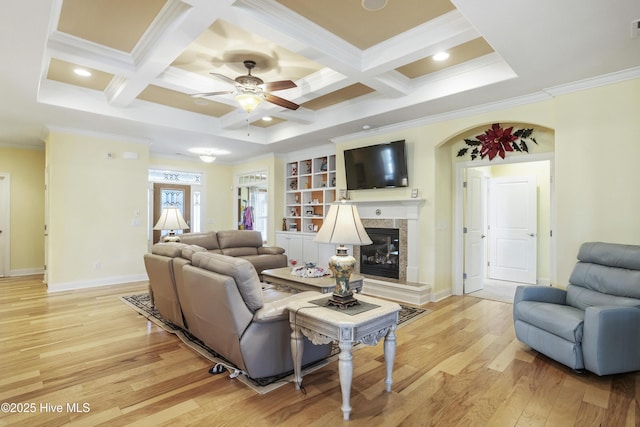 living area with a tiled fireplace, light wood-style floors, coffered ceiling, and ornamental molding