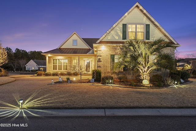 view of front of property featuring a standing seam roof, brick siding, and metal roof