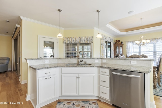 kitchen with light wood finished floors, a sink, backsplash, and stainless steel dishwasher