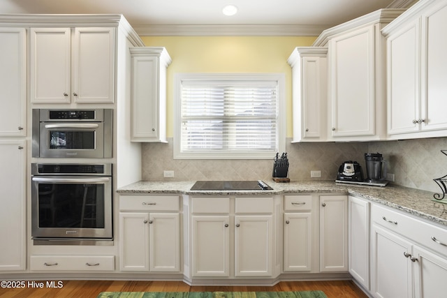 kitchen featuring decorative backsplash, black electric stovetop, ornamental molding, and white cabinetry