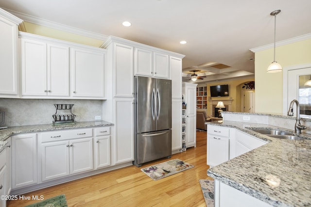 kitchen featuring a sink, ornamental molding, white cabinets, and freestanding refrigerator