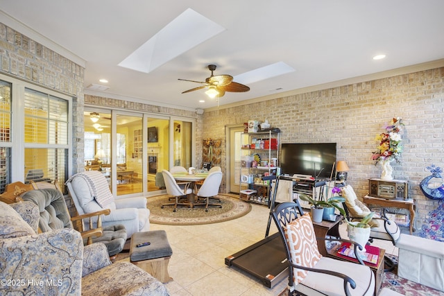 living room featuring ceiling fan, a skylight, brick wall, and tile patterned flooring