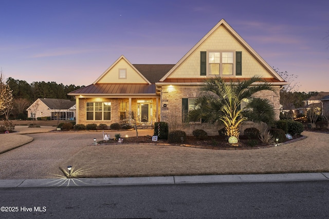 view of front of home featuring brick siding, metal roof, and a standing seam roof