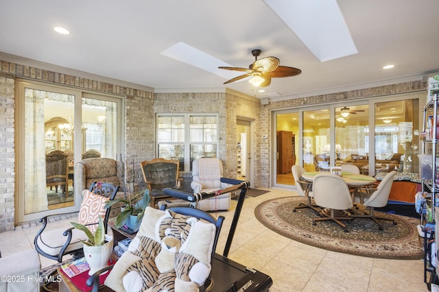 interior space featuring a skylight, brick wall, and ceiling fan