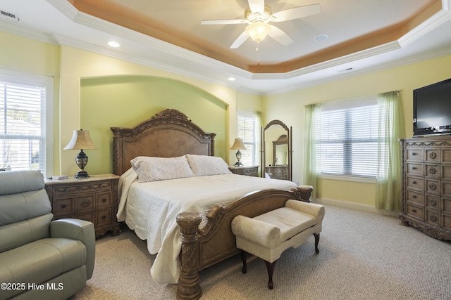 bedroom featuring multiple windows, light colored carpet, and a tray ceiling