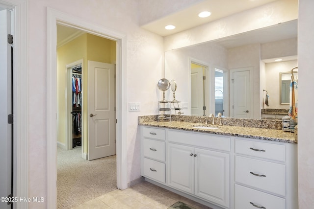 bathroom with vanity, a spacious closet, recessed lighting, and baseboards