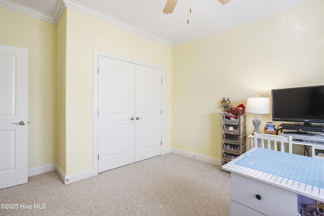 carpeted bedroom with a closet, baseboards, ceiling fan, and crown molding