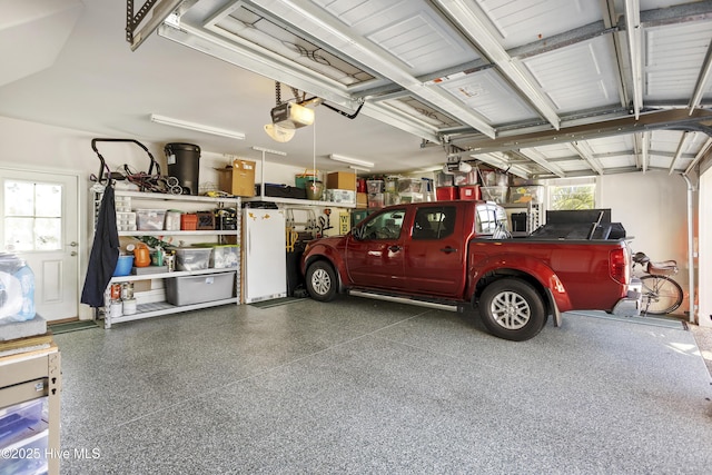 garage with freestanding refrigerator and a garage door opener