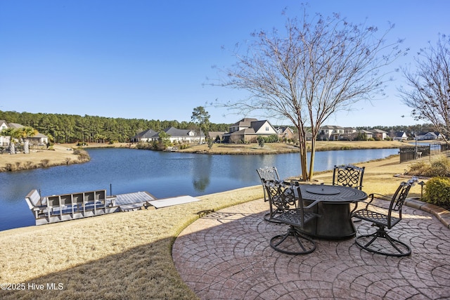 view of patio / terrace with a residential view, outdoor dining area, a boat dock, and a water view