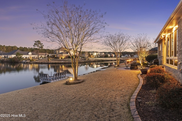 yard at dusk with a fire pit and a water view