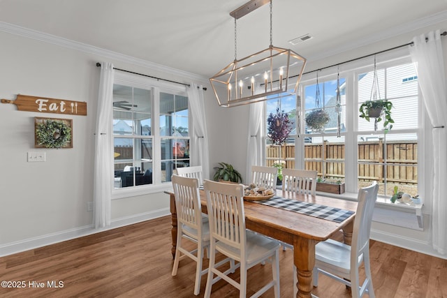 dining area featuring visible vents, baseboards, a chandelier, ornamental molding, and wood finished floors