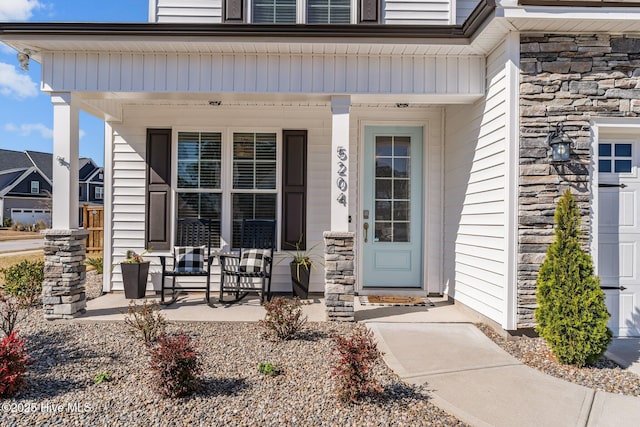 view of exterior entry featuring stone siding and a porch