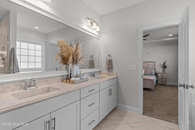 ensuite bathroom featuring double vanity, connected bathroom, baseboards, and a sink