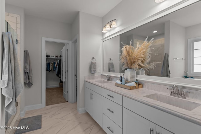 full bath featuring a sink, a walk in closet, a stall shower, and double vanity