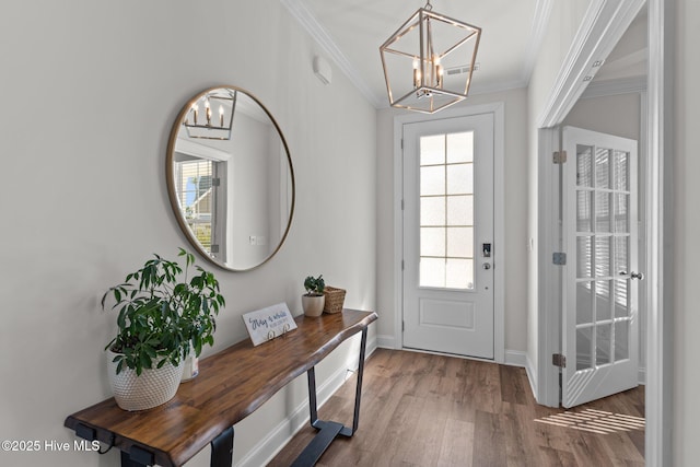 doorway with wood finished floors, baseboards, visible vents, crown molding, and a notable chandelier