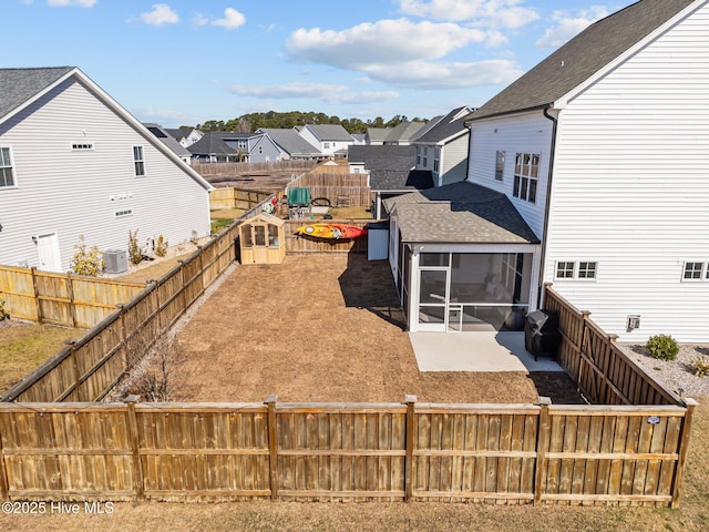 view of yard with a patio, central AC, a fenced backyard, a residential view, and a sunroom