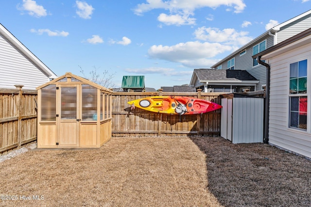 view of yard with an outbuilding, a fenced backyard, and an exterior structure