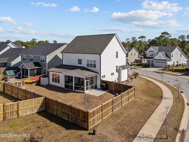 back of property with a residential view, a shingled roof, a fenced backyard, and a sunroom