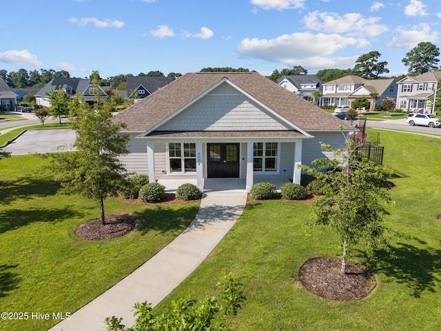 view of front of home featuring a residential view, covered porch, roof with shingles, and a front yard