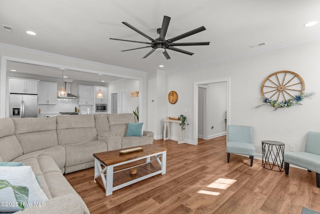 living room with light wood-style flooring, a ceiling fan, and crown molding